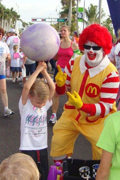 Ronald McDonald helps a young Komen racer with spinning the ball.